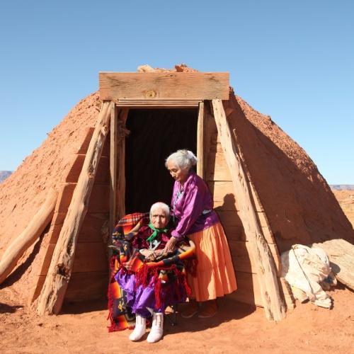 2 Navajo-vrouwen buiten hun traditionele Hogan-hut